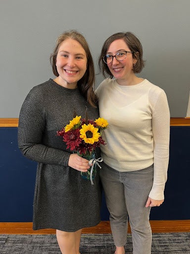 a mentor and mentee smiling with flowers