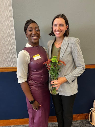 a mentor and mentee smiling with flowers